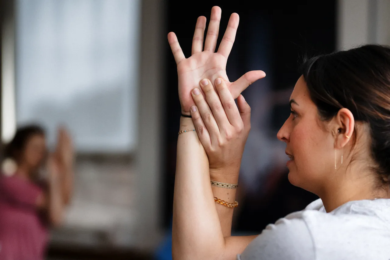 Des élèves dans un studio lèvent les mains pendant un cours